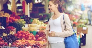 Gestante feliz e ecolhendo alimentos na feirinha